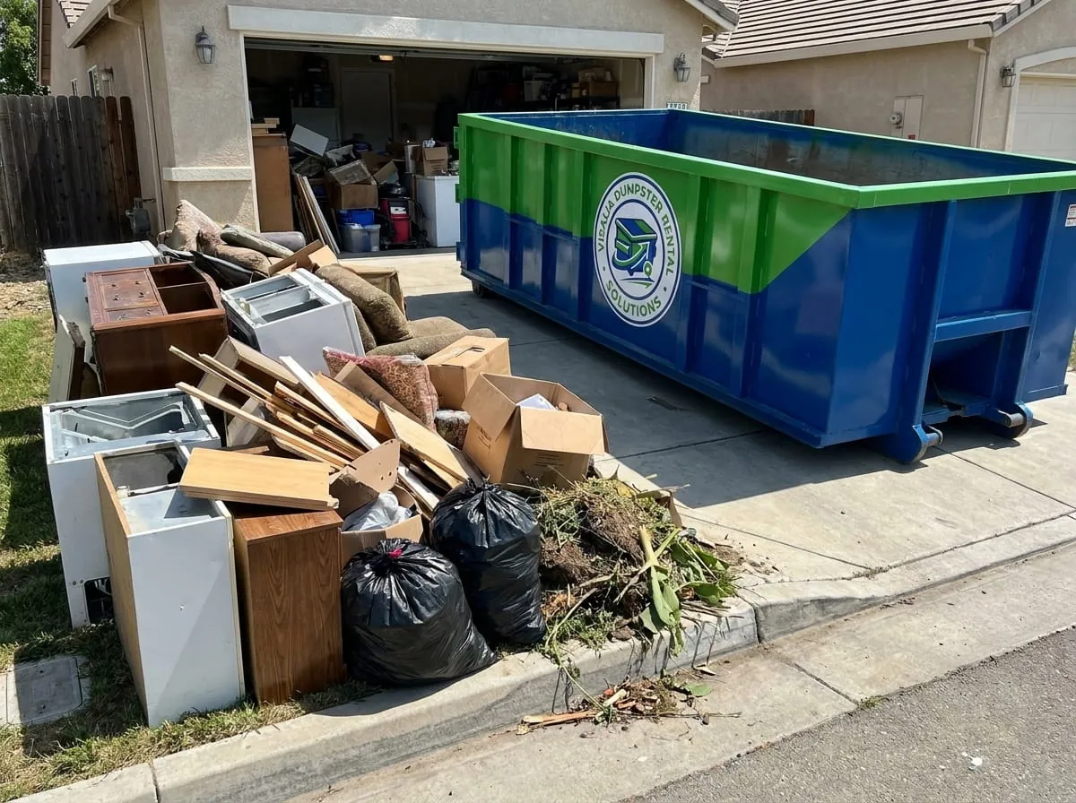 Roll-off container beside a large household clearance pile in Visalia, California Roll-off container beside a large household clearance pile in Visalia, California